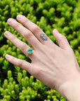 Large green gemstone ring on hand with tattoo 