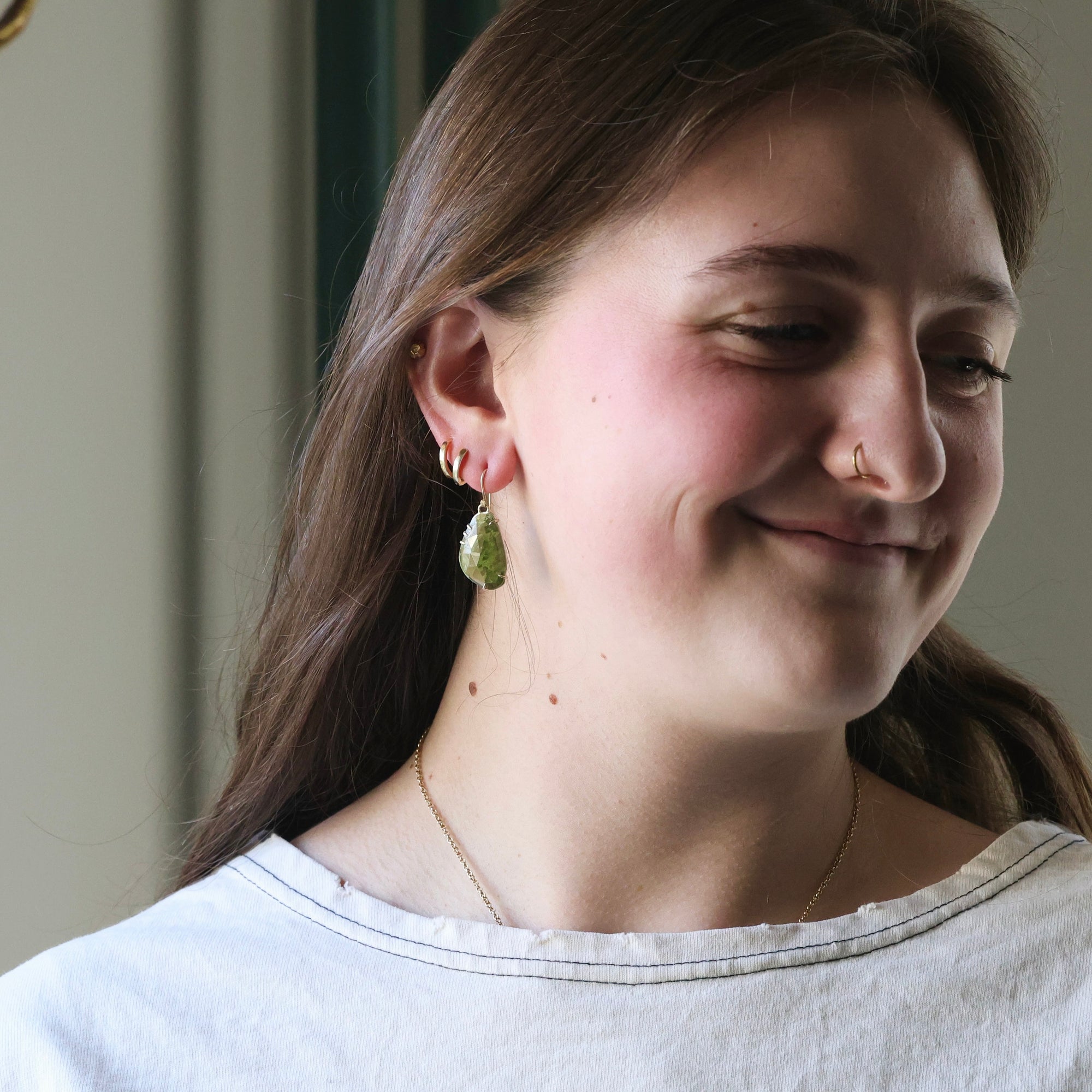 Woman wearing earrings and a nose ring, with a neutral background