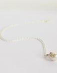 Pearl necklace with a heart-shaped pendant on a light gray background