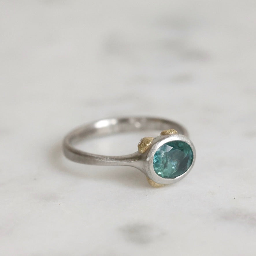 Silver ring with a green gemstone on a light gray background