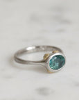 Silver ring with a green gemstone on a light gray background