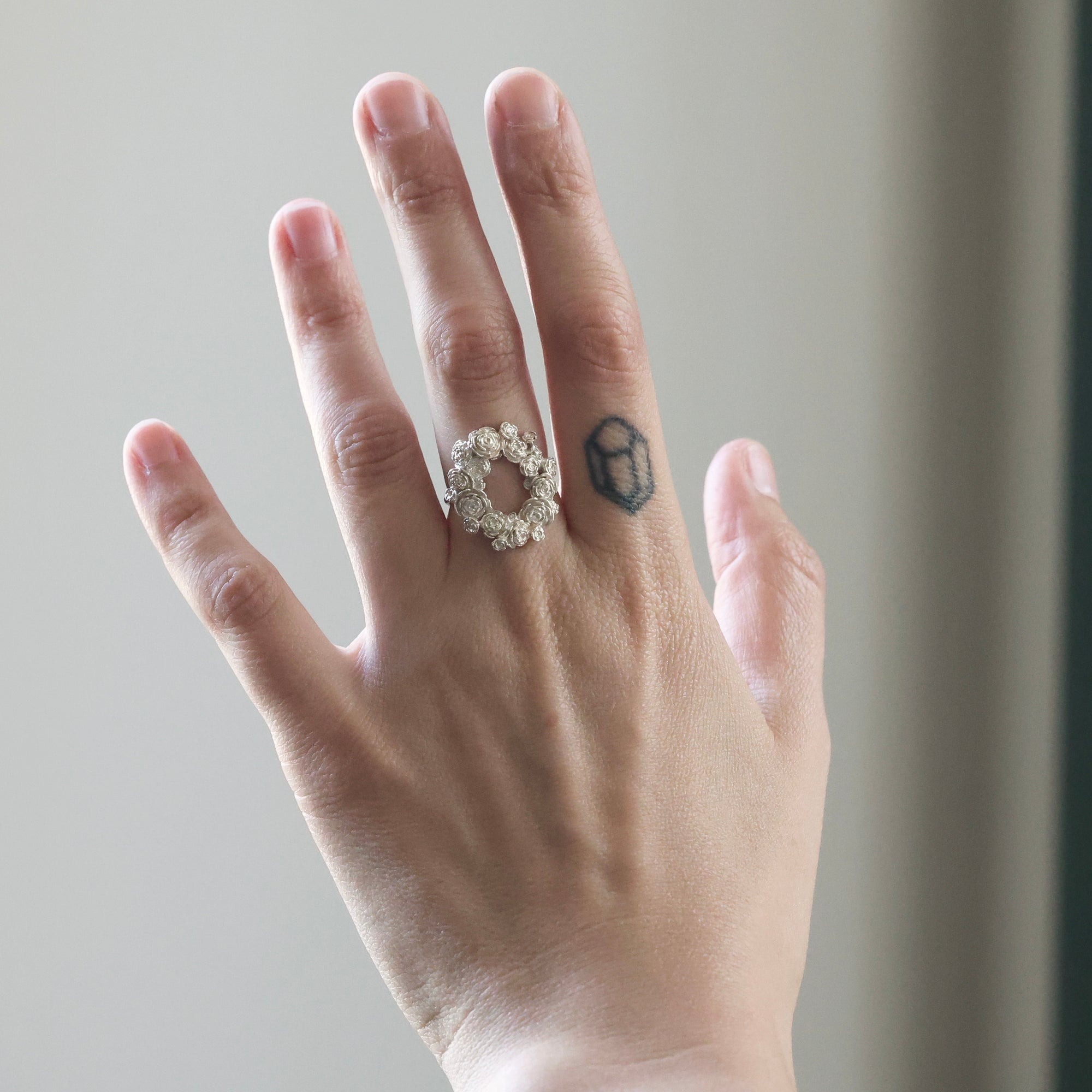 Hand wearing a silver ring with a blurred background