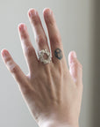 Hand wearing a silver ring with a blurred background