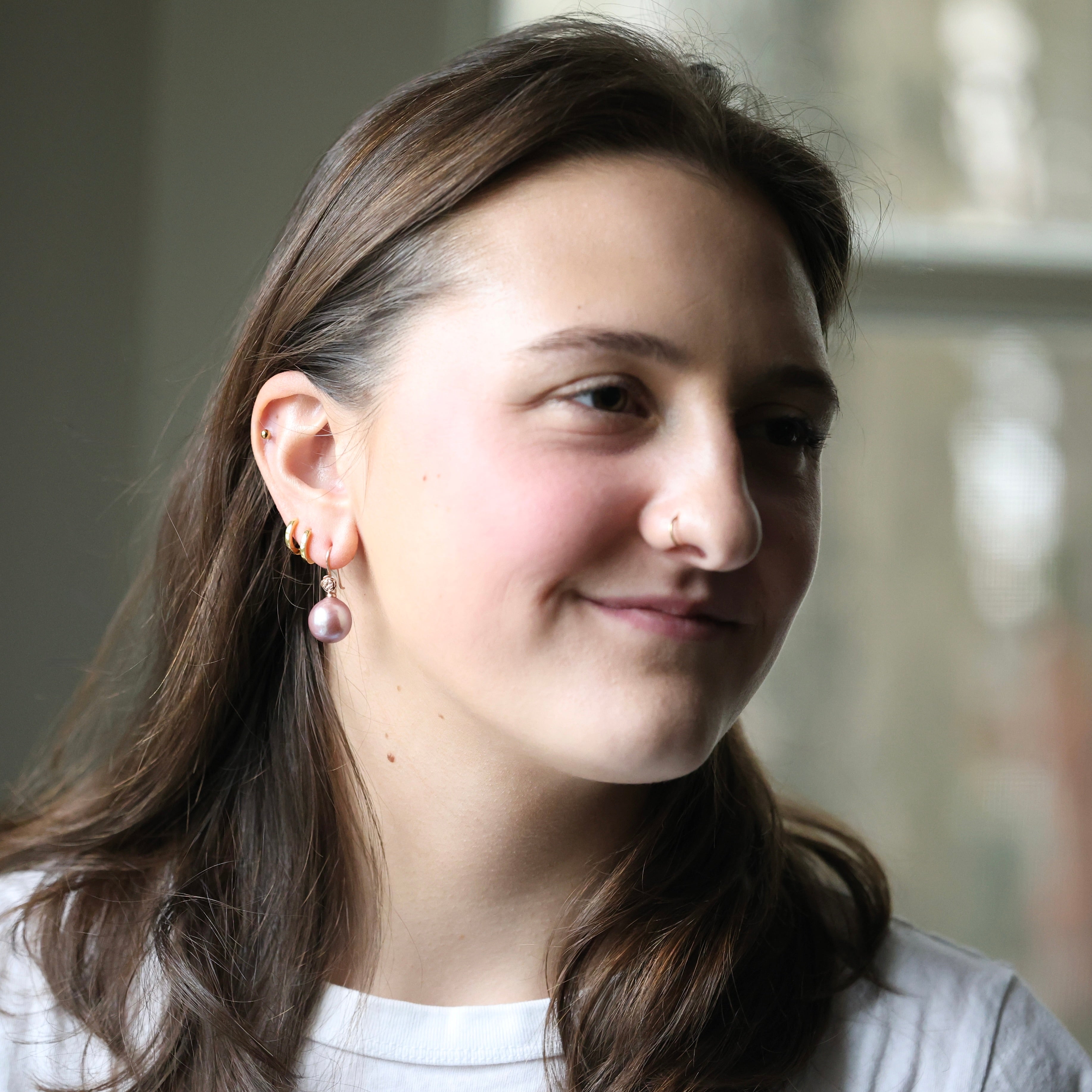 Woman with long brown hair wearing earrings, smiling.