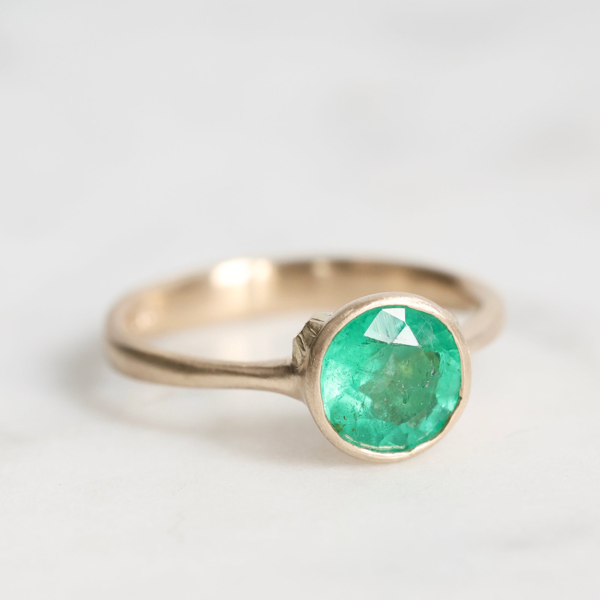 Gold ring with a green gemstone on a white background