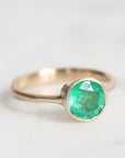 Gold ring with a green gemstone on a white background