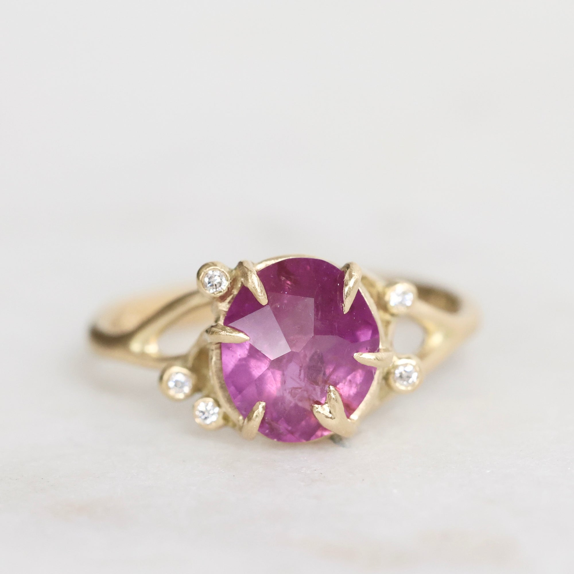 Gold ring with a purple gemstone on a light gray background