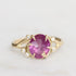 Gold ring with a purple gemstone on a light gray background