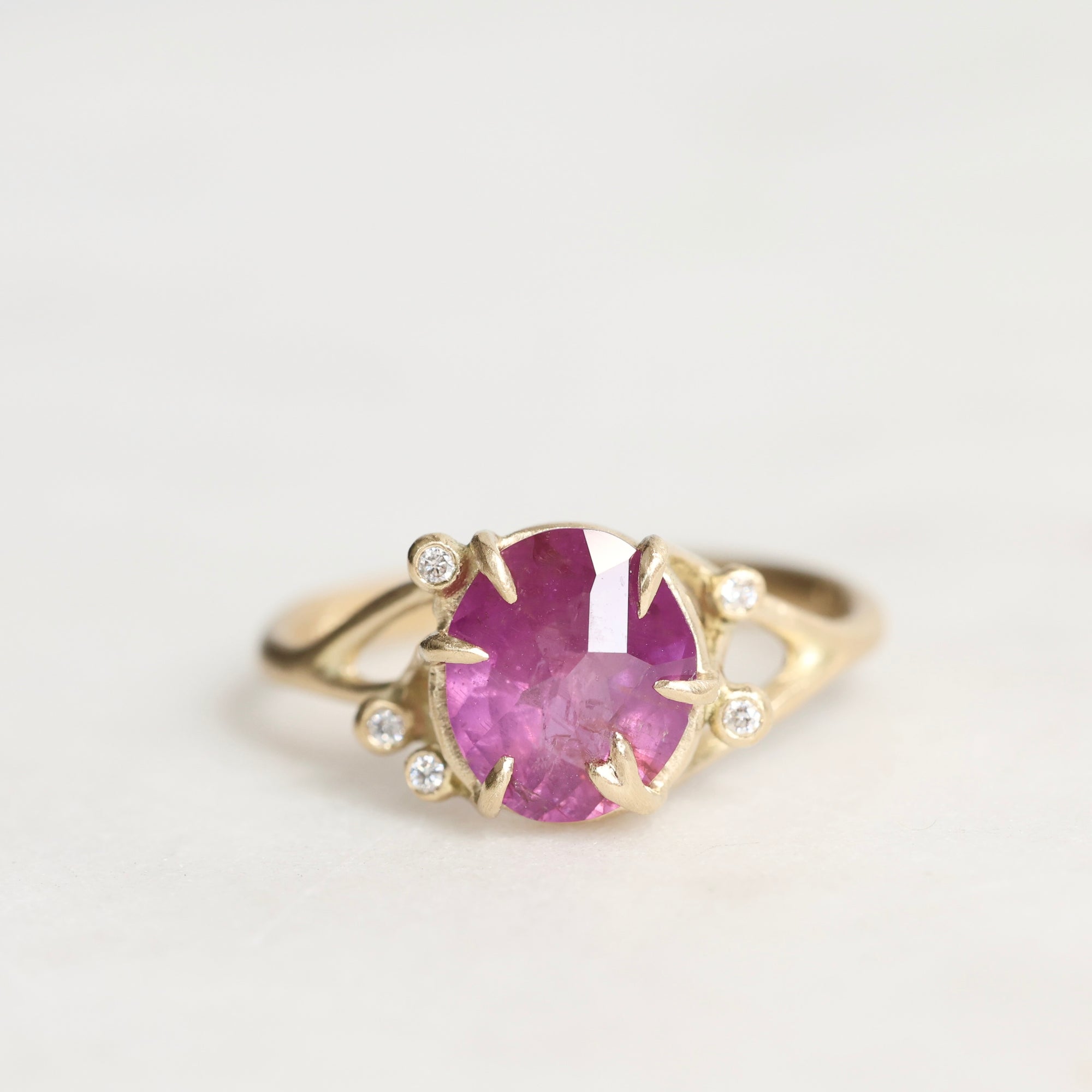 Gold ring with a pink gemstone on a light gray background
