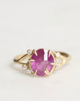Gold ring with a pink gemstone on a light gray background