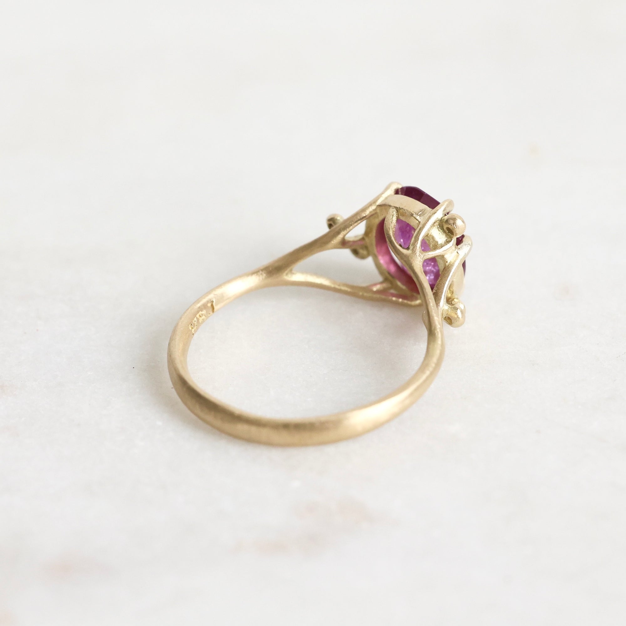 Gold ring with a purple gemstone on a white background