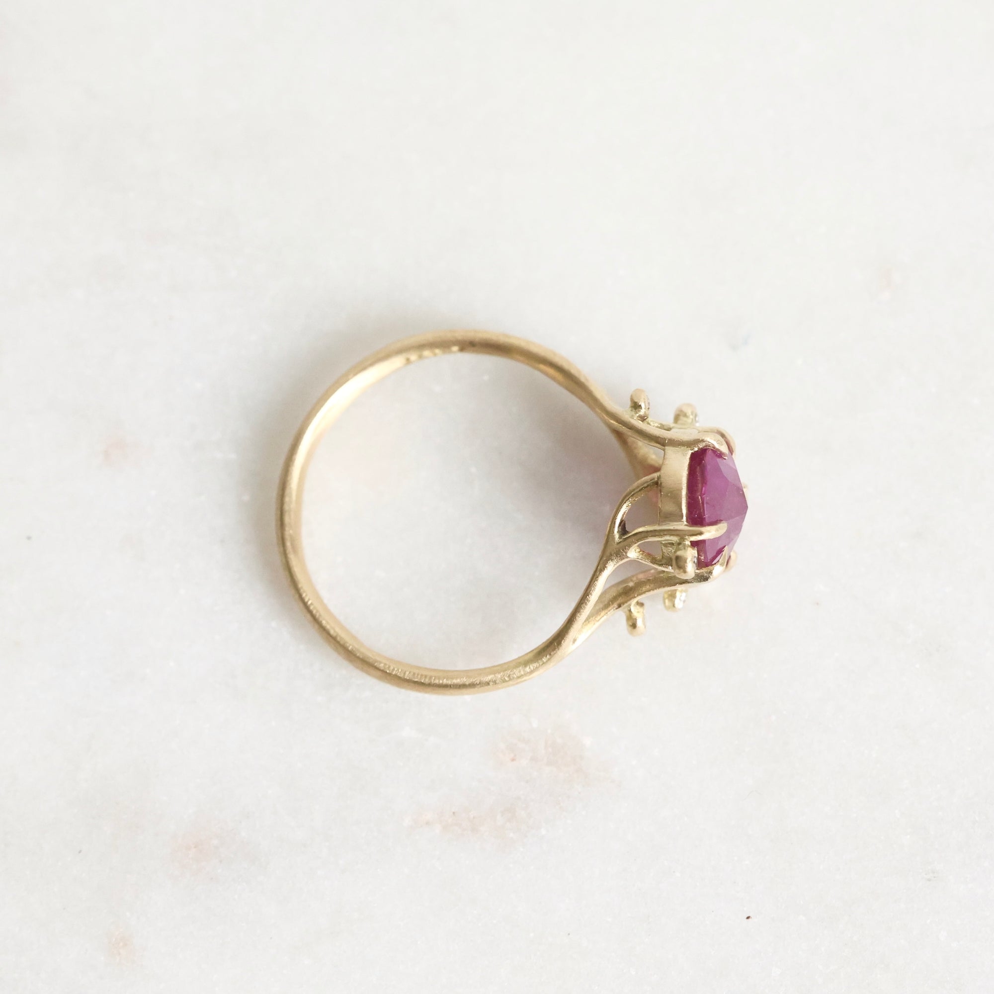 Gold ring with a purple gemstone on a light gray background