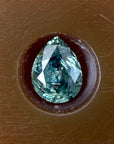 Teal gemstone in a brown setting on a brown background