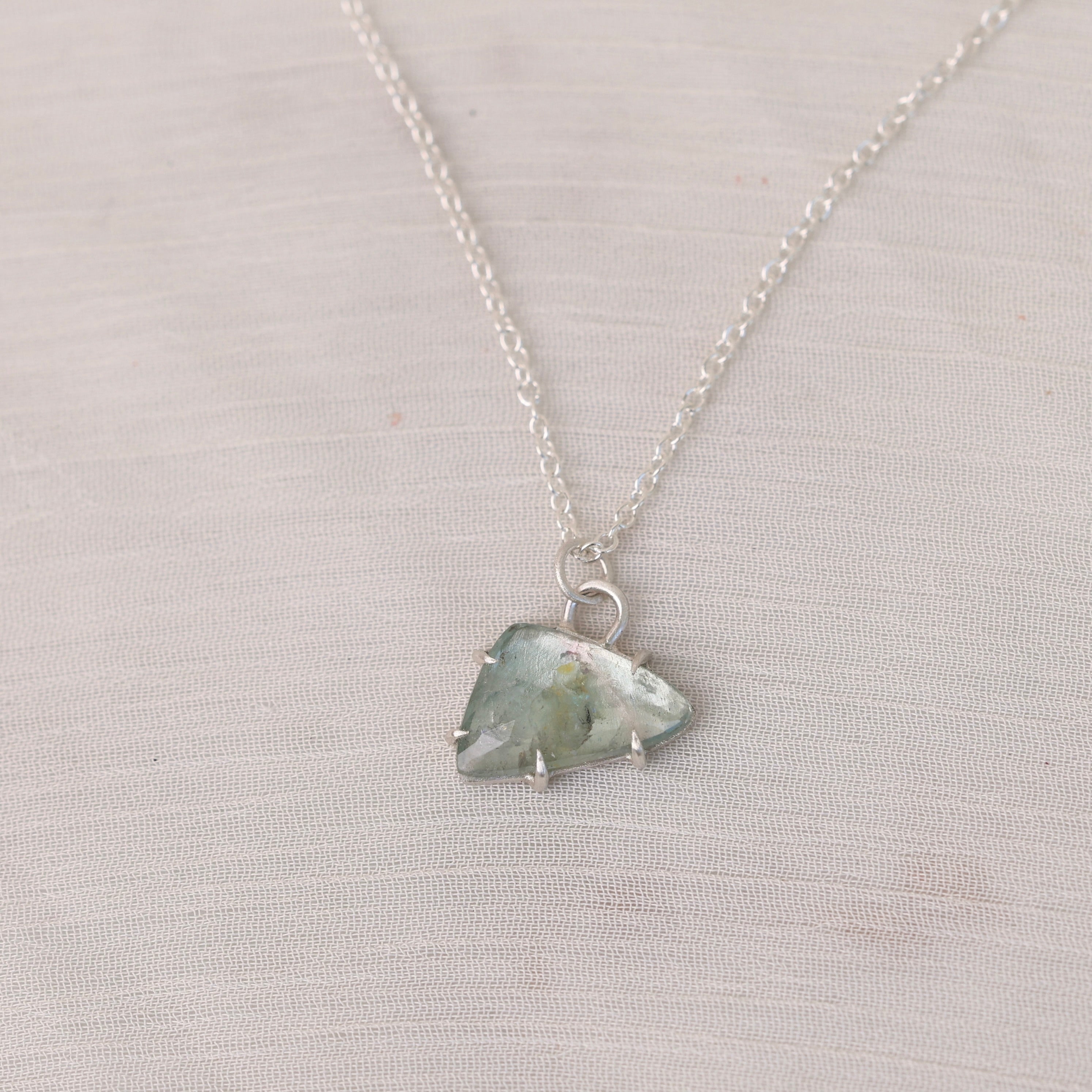 Necklace with a green crystal pendant on a light gray background
