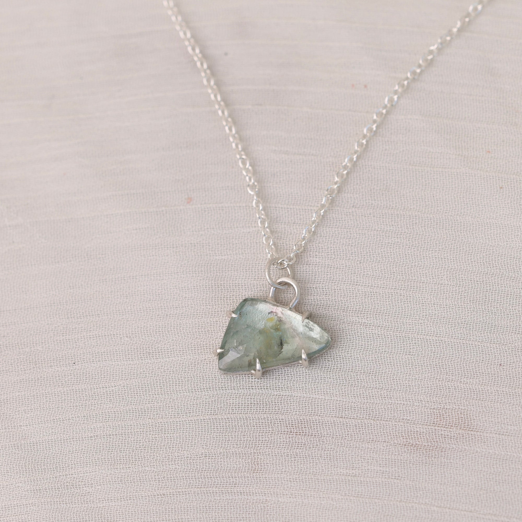 Necklace with a green crystal pendant on a light gray background