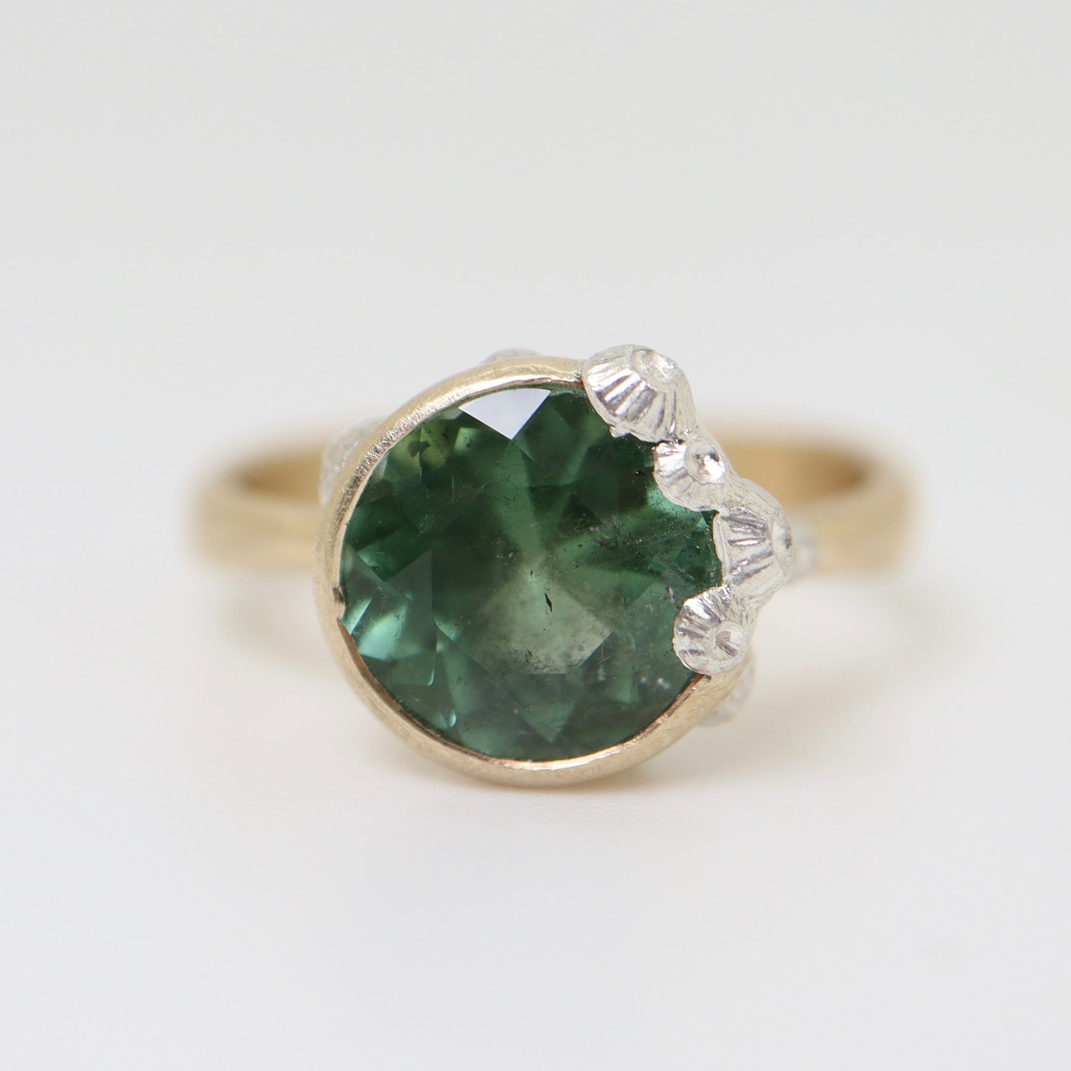 A 2.74ct tourmaline ring. The tourmaline is a deep green and is set in 14k gold with a 14k gold band. The rsetting is encrusted with bright sterling silver barnacles.