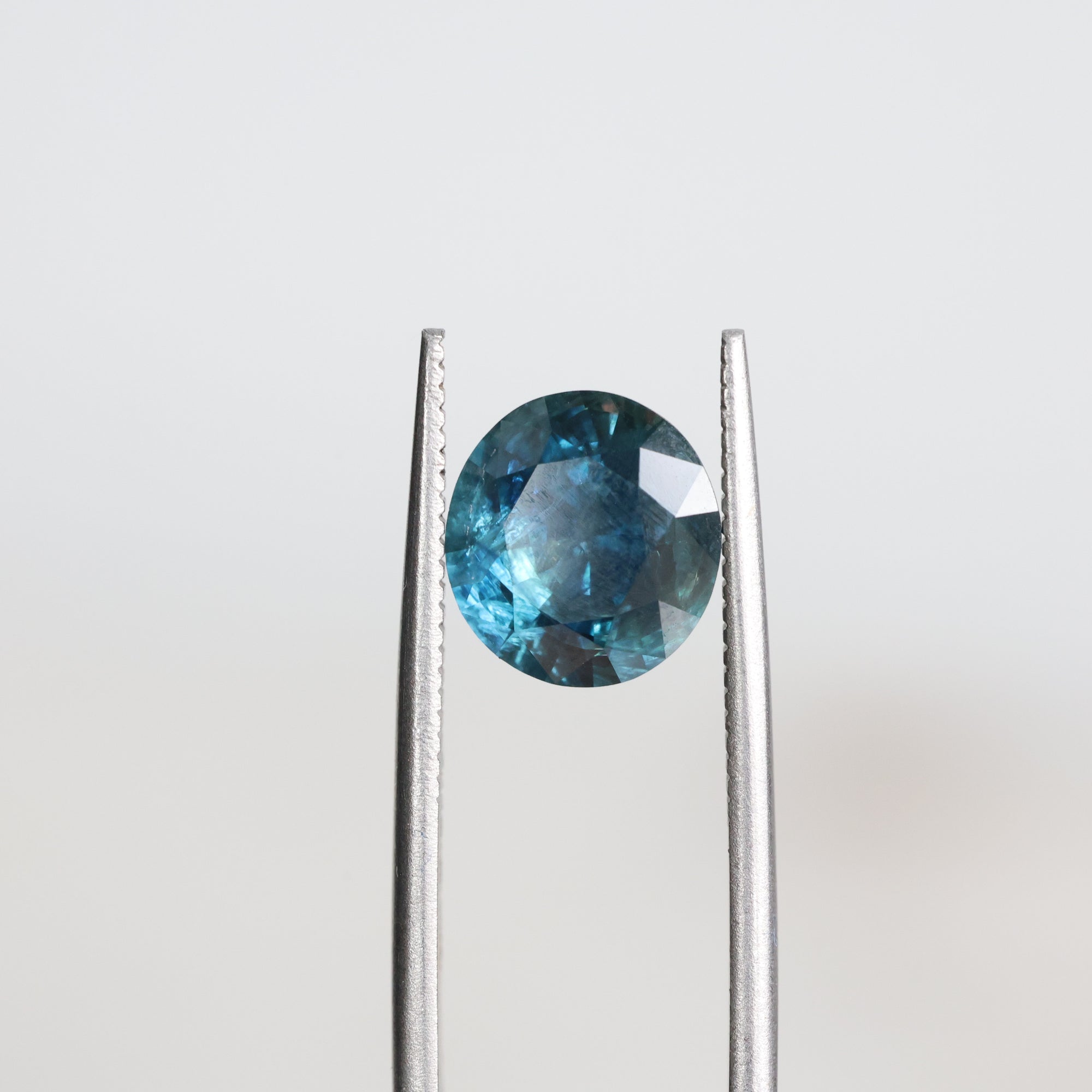 Blue included sapphire held in tweezers