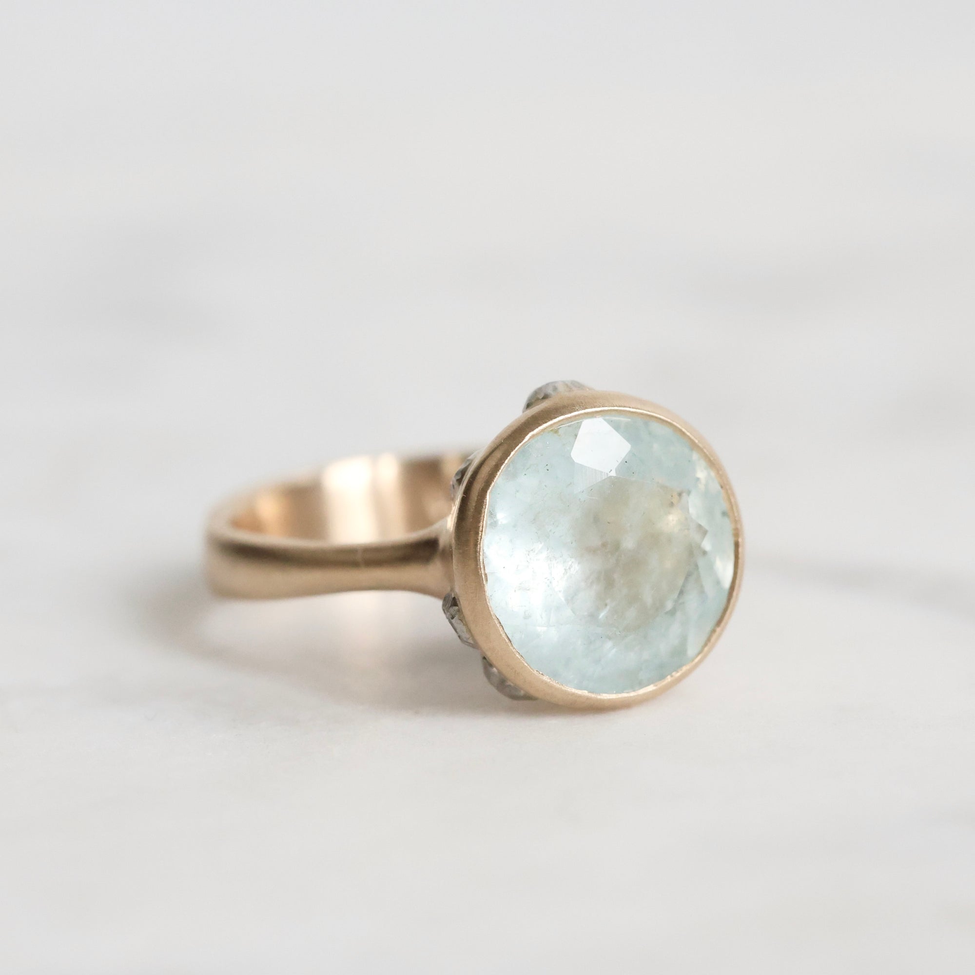 Gold ring with a large, faceted aquamarine stone on a light background