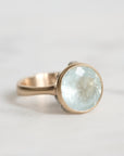 Gold ring with a large, faceted aquamarine stone on a light background