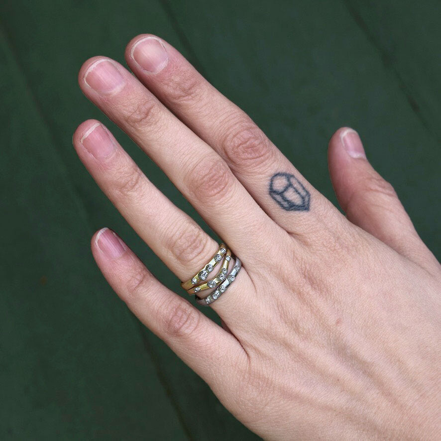 Hand with a small tattoo on the ring finger against a green background