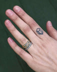 Hand with a small tattoo on the ring finger against a green background