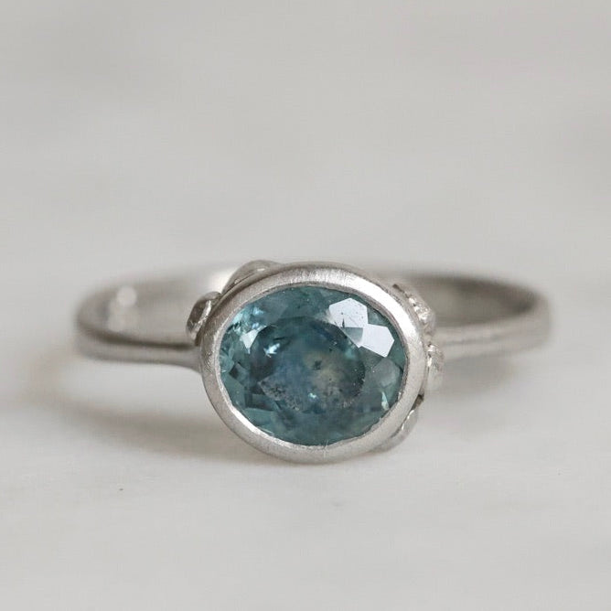 Silver ring with a blue gemstone on a light gray background