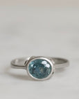 Silver ring with a blue gemstone on a light gray background