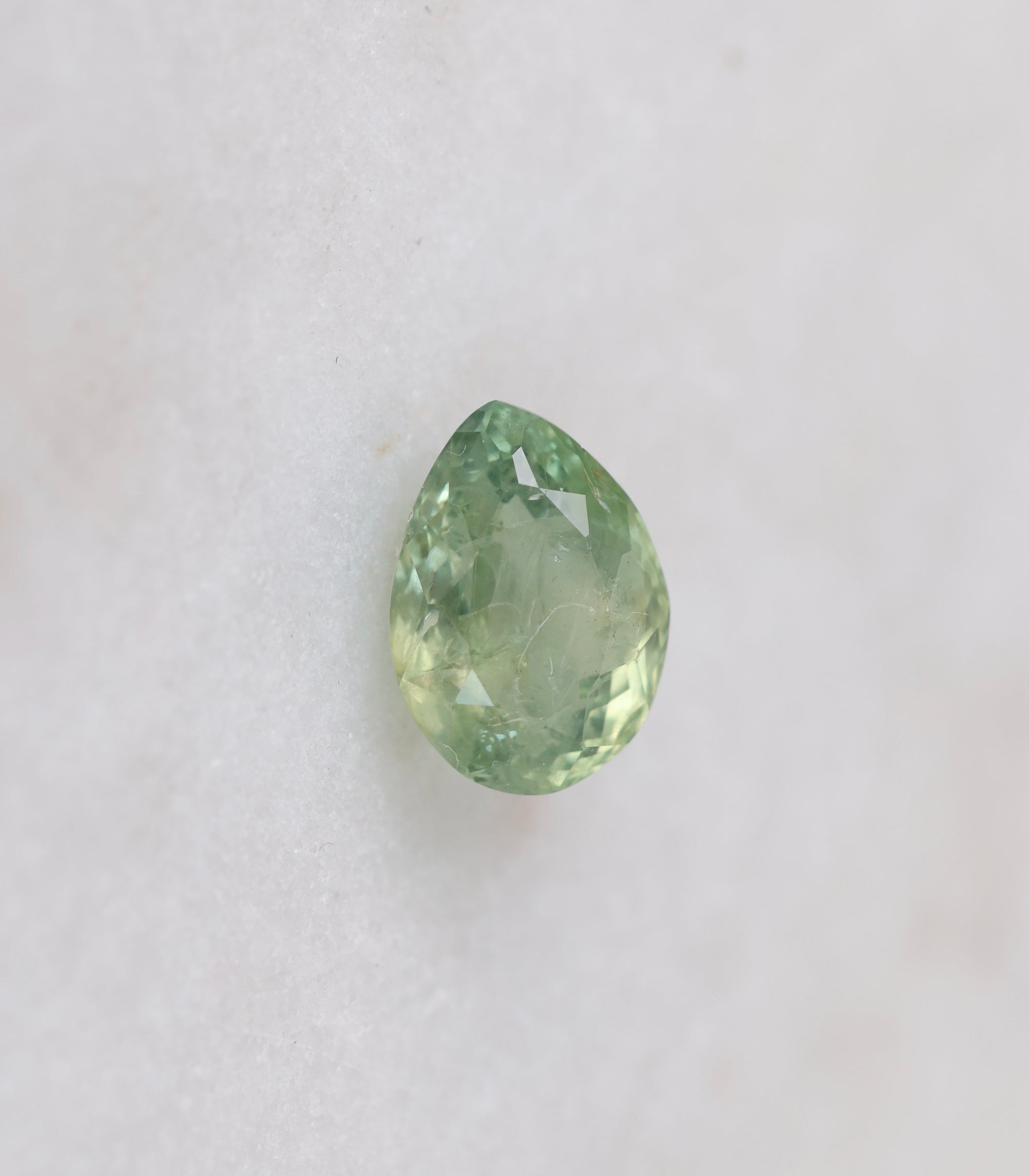 Teardrop-shaped green gemstone on a white background