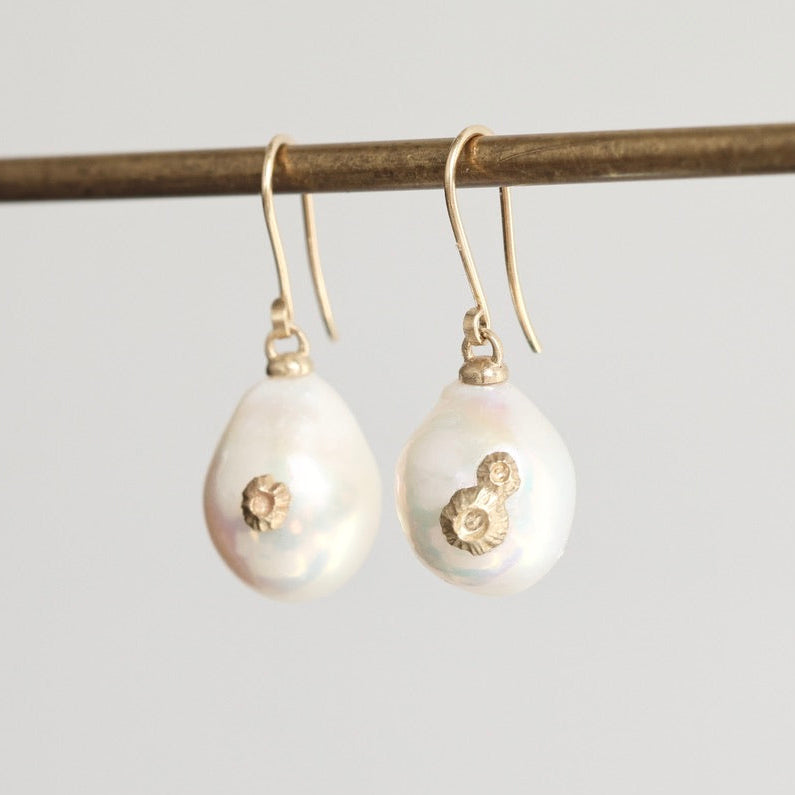 Pearl earrings with gold accents on a gray background