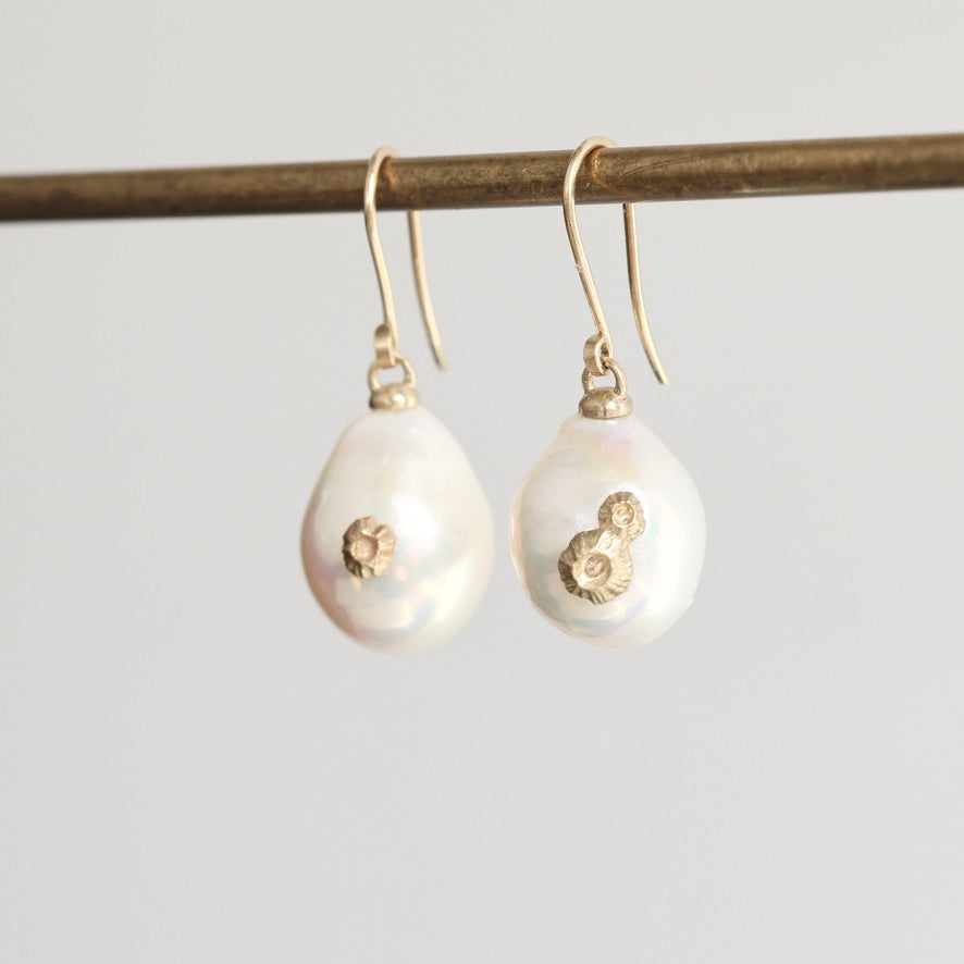 Pearl earrings with gold accents on a gray background