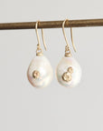 Pearl earrings with gold accents on a gray background