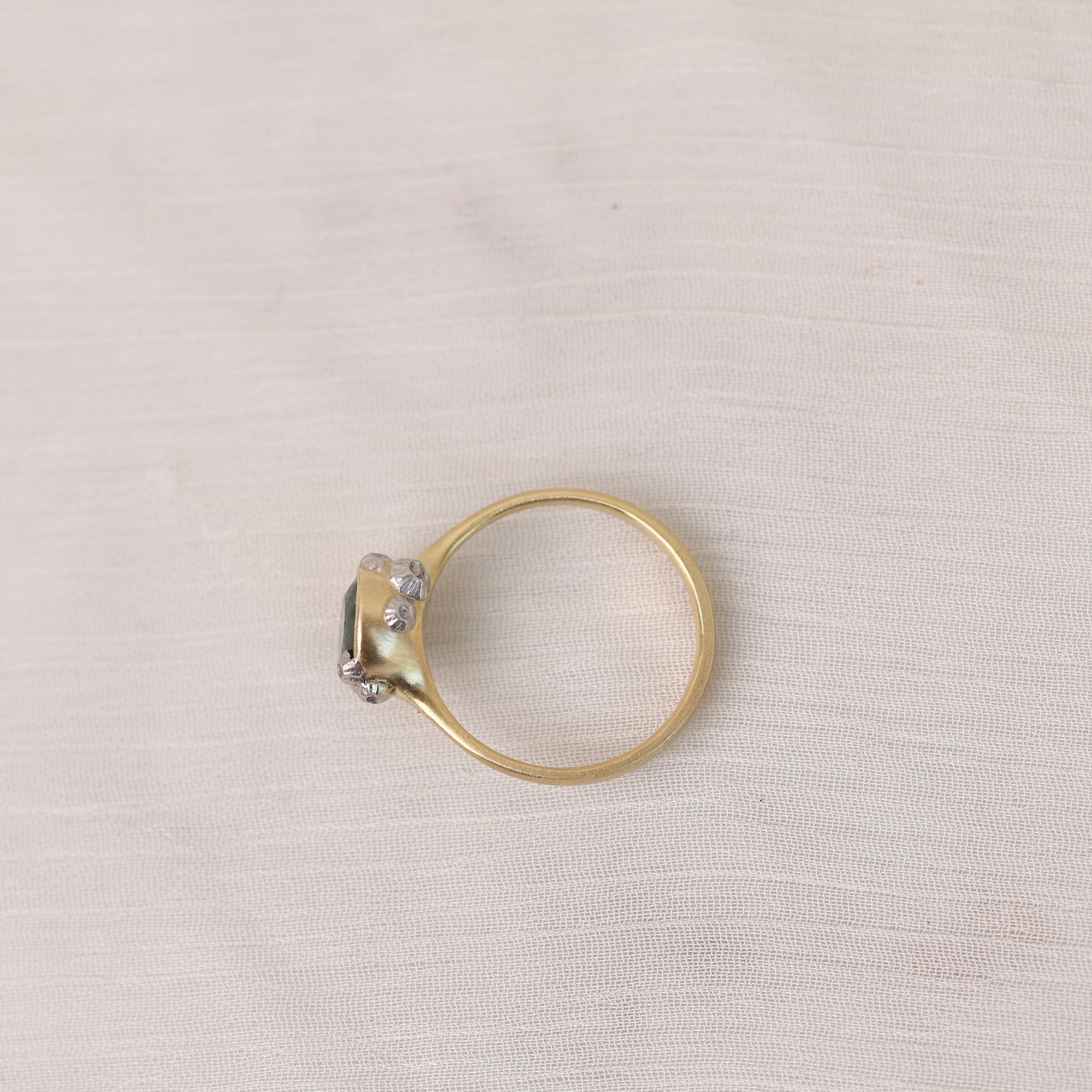 Gold ring with a diamond on a light gray fabric background