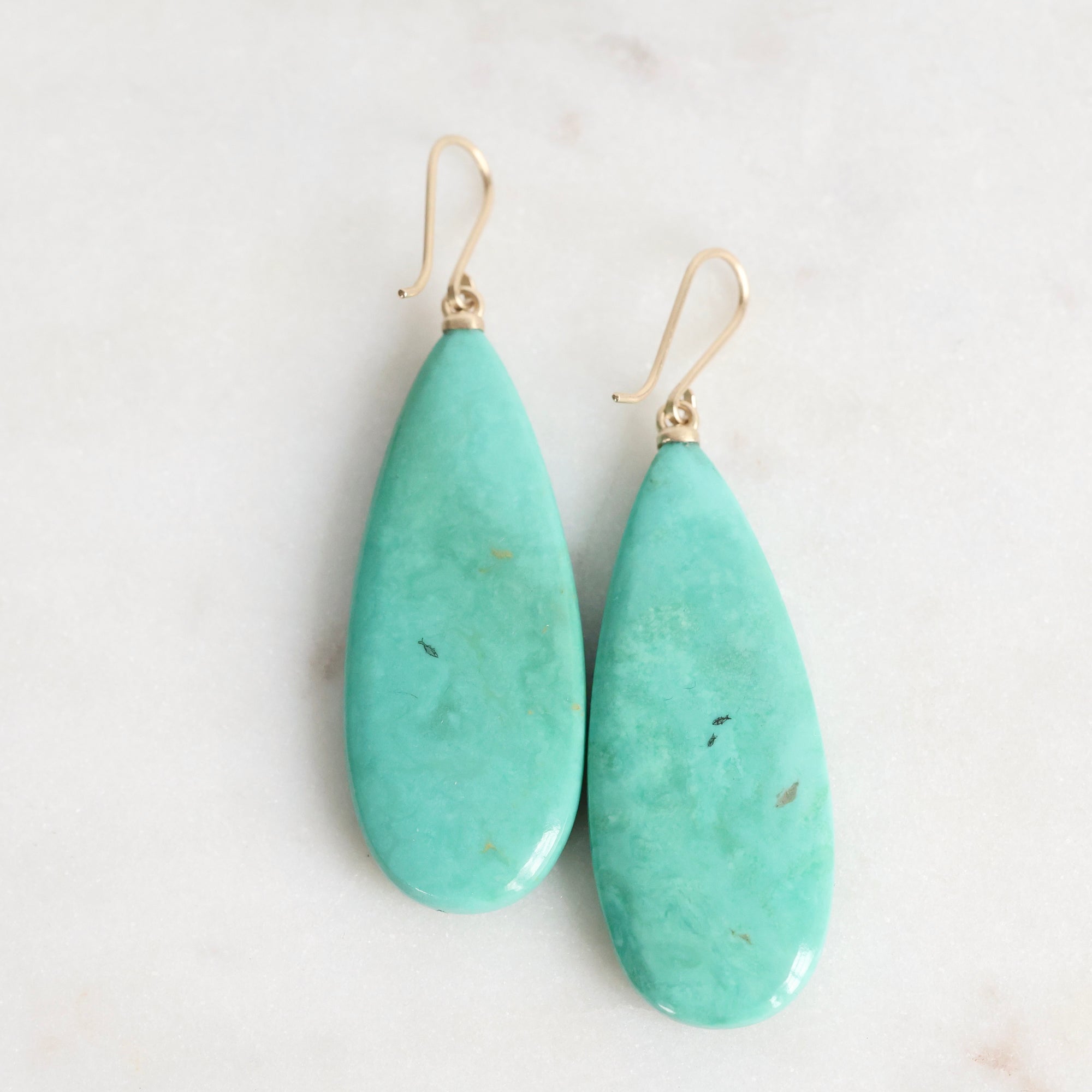 Teal teardrop earrings on a light background