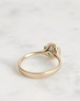 Gold ring with a small green gemstone on a light gray background