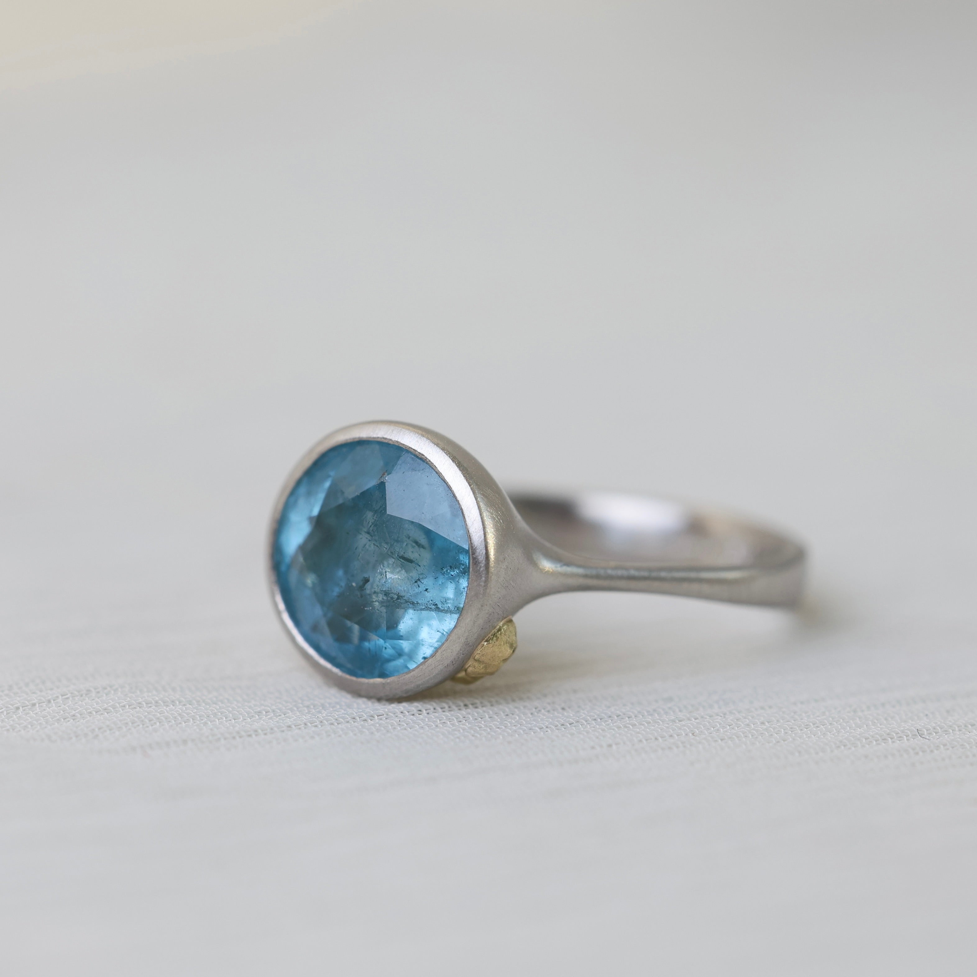 Silver ring with a blue gemstone on a light gray background