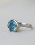 Silver ring with a blue gemstone on a light gray background