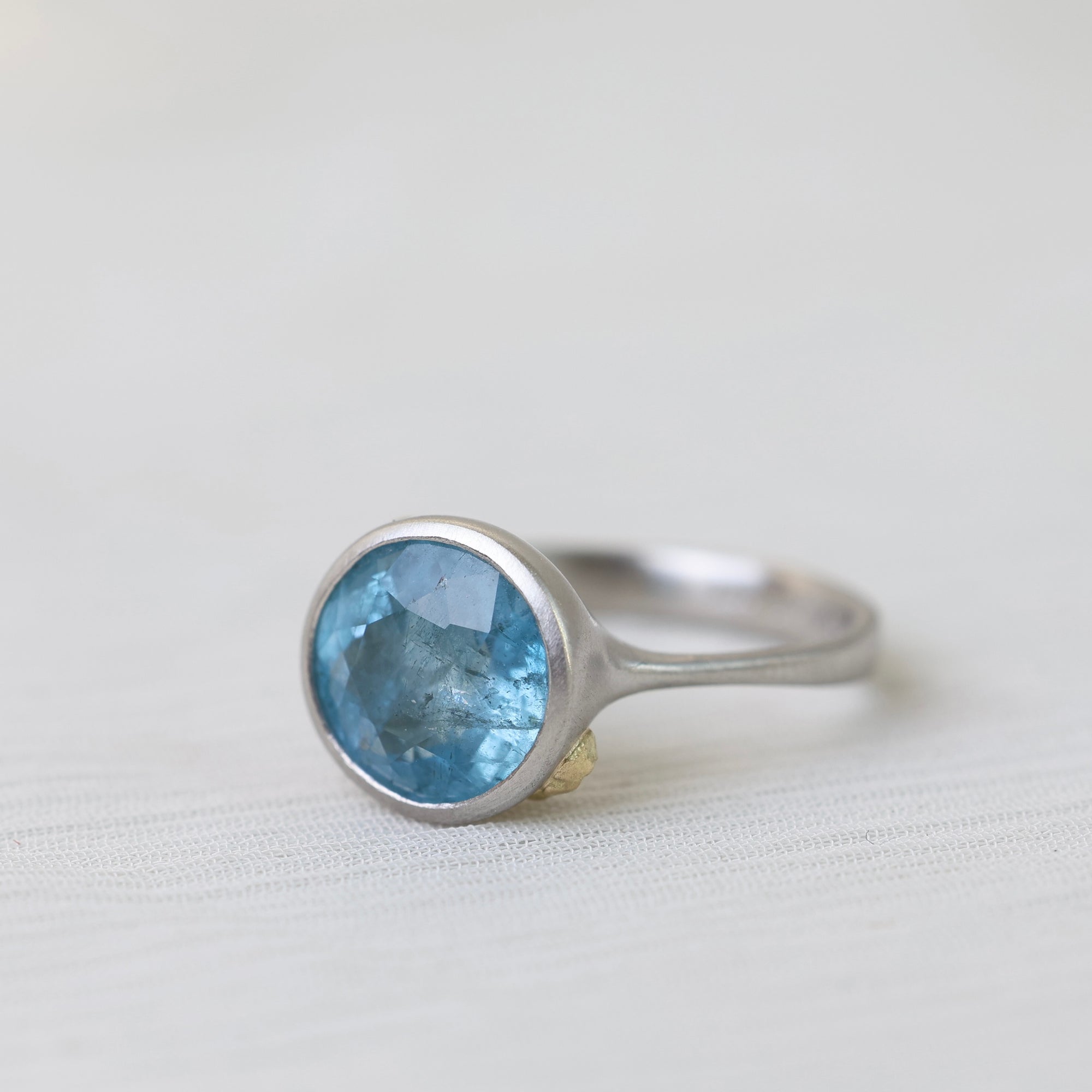Silver ring with a blue gemstone on a light gray background
