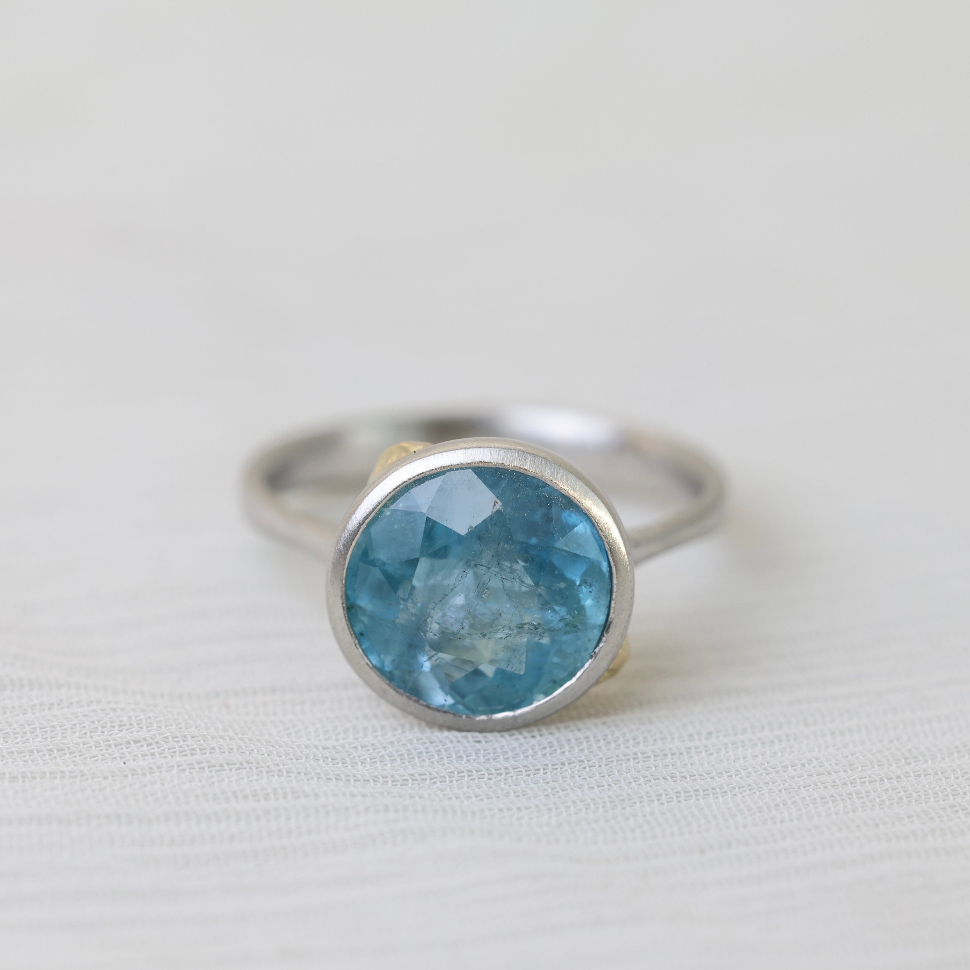 Silver ring with a blue gemstone on a light gray background