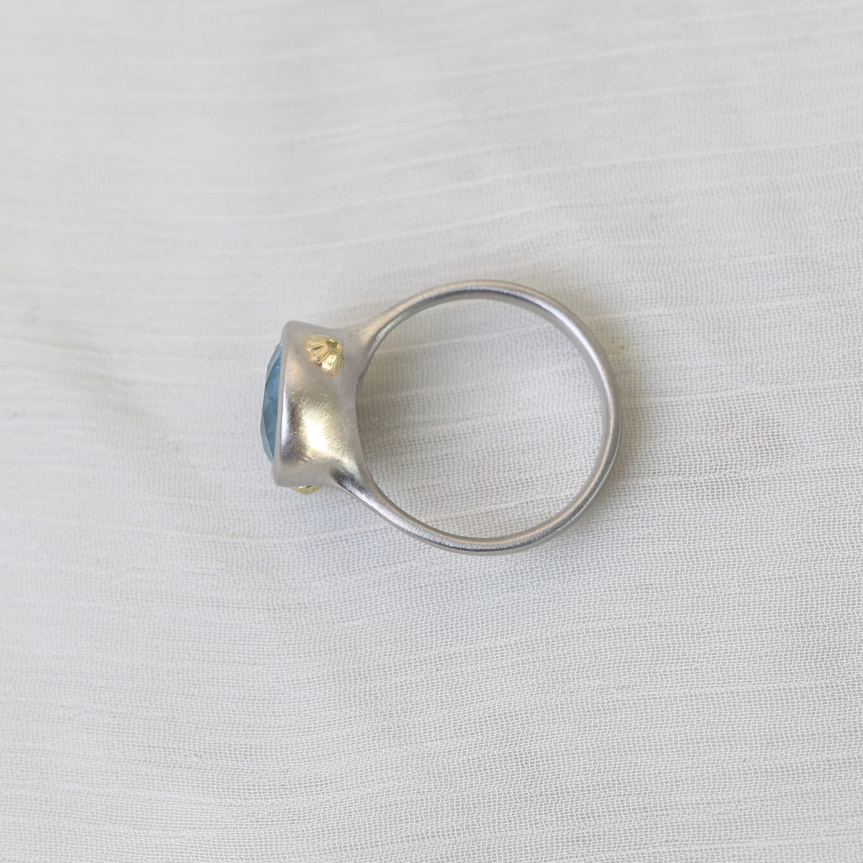 Silver ring with a blue gemstone on a light gray background