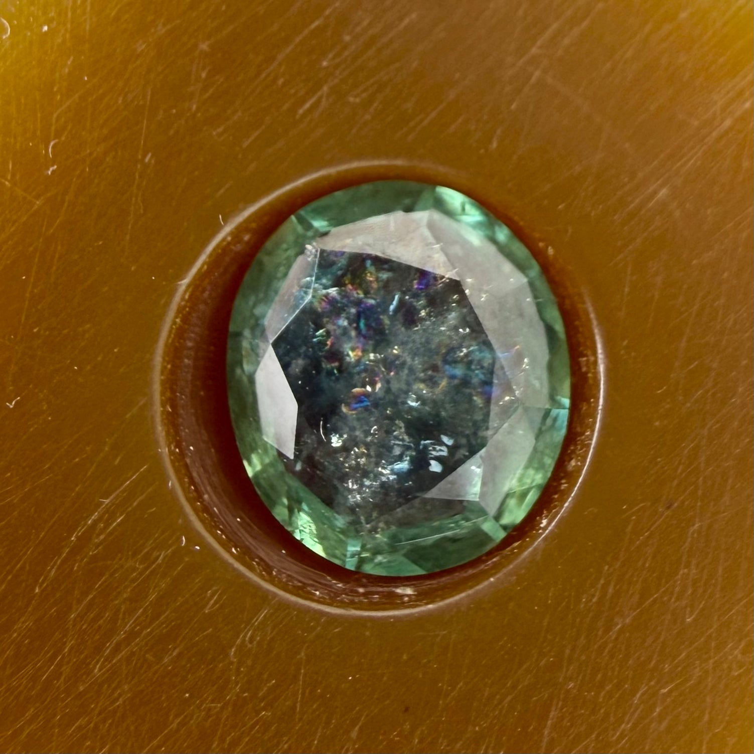 green gemstone in a brown setting