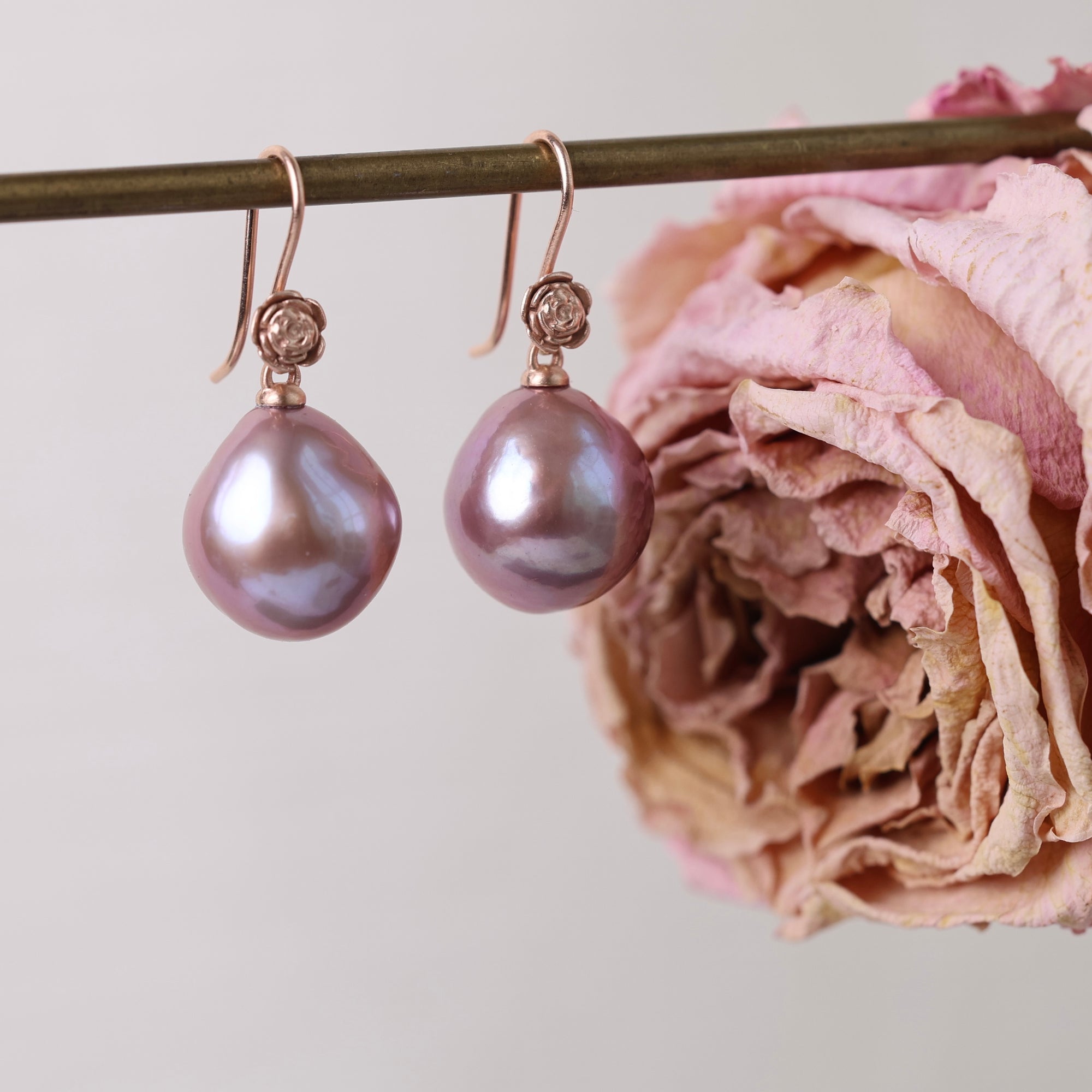 Pink pearl earrings on a stand with a pink flower.