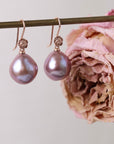 Pink pearl earrings on a stand with a pink flower.