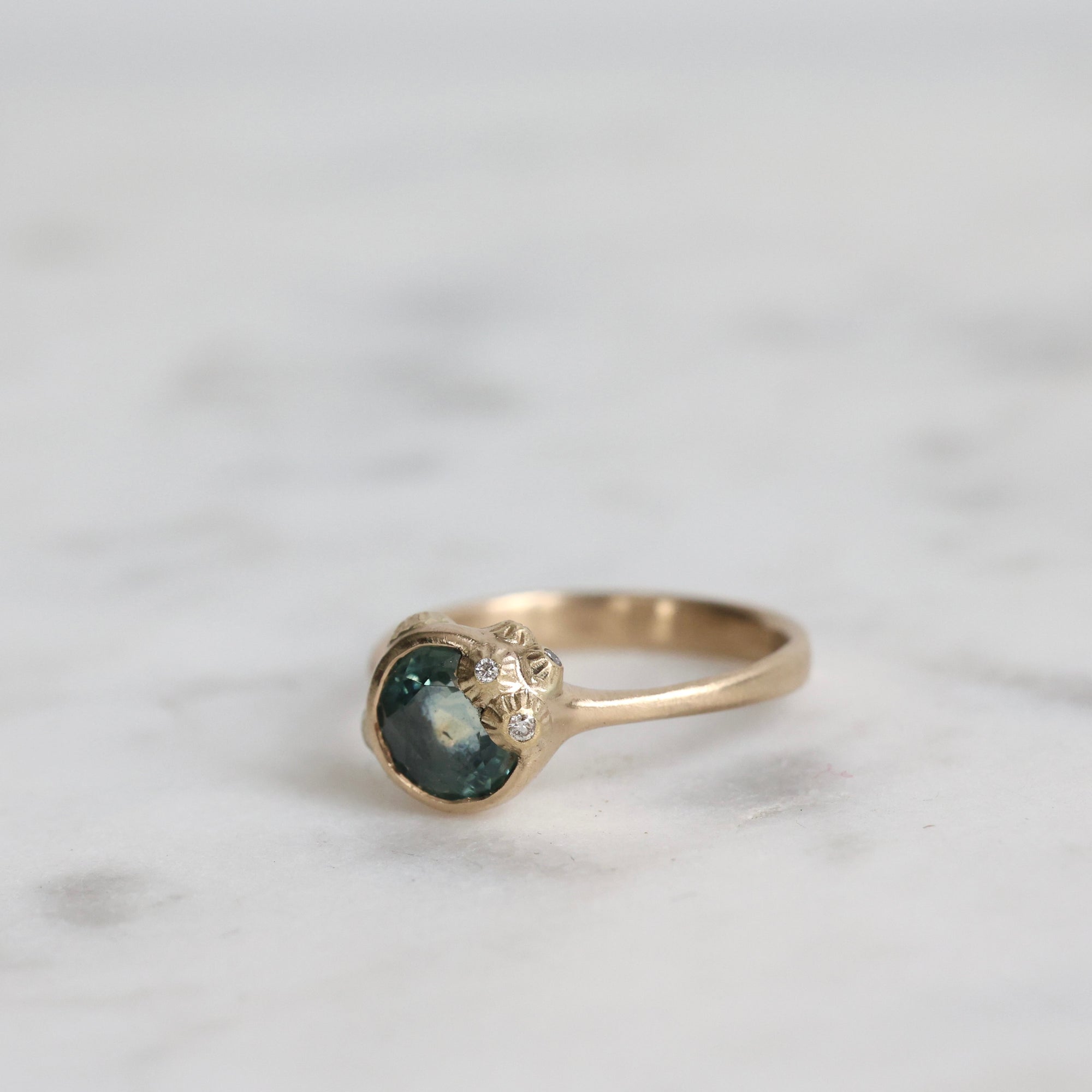 Gold ring with a gemstone on a marble surface