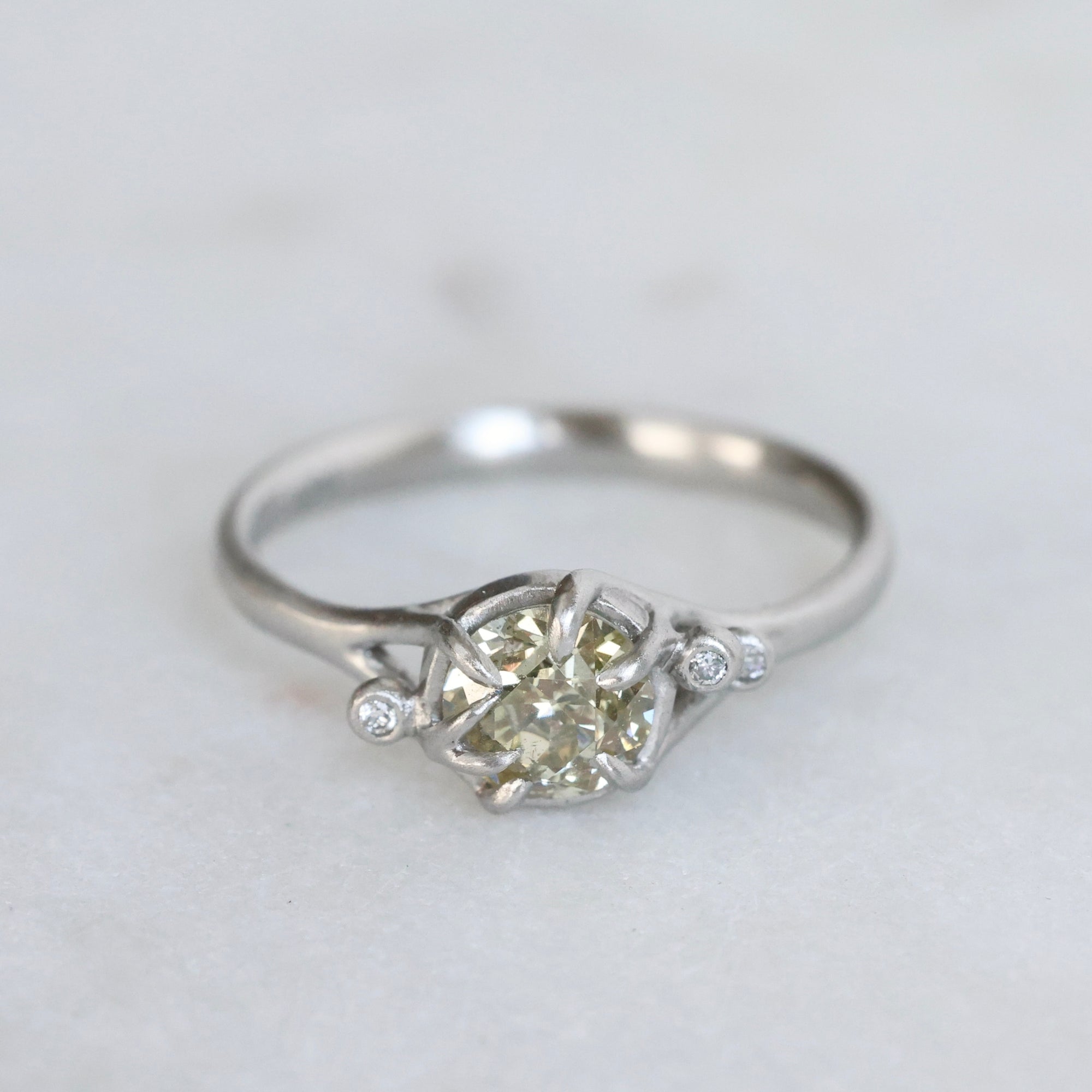 Silver ring with a diamond on a light gray background