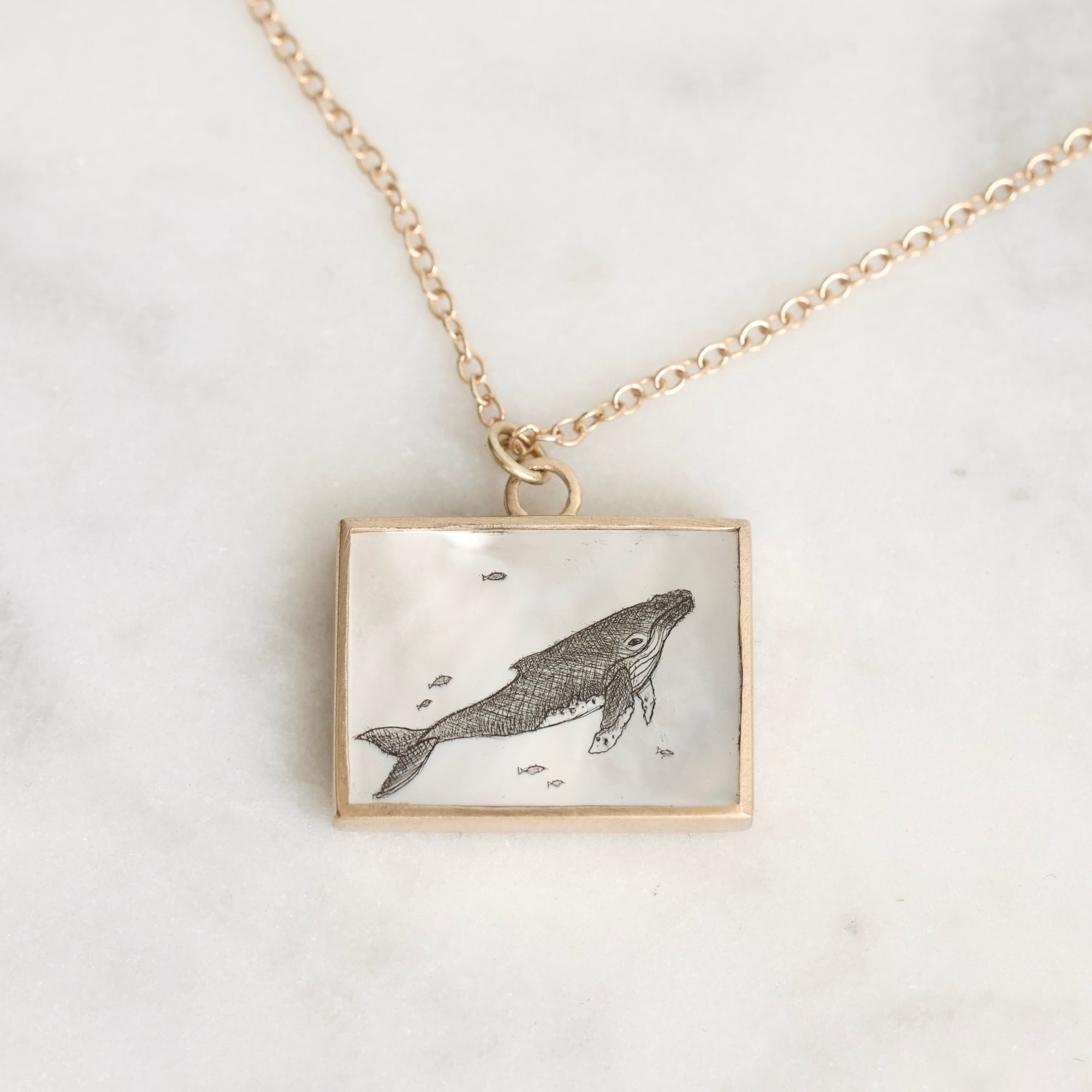Necklace with a pendant featuring an engraved whale design on a light background