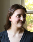 Woman with a slight smile in front of a window with greenery outside