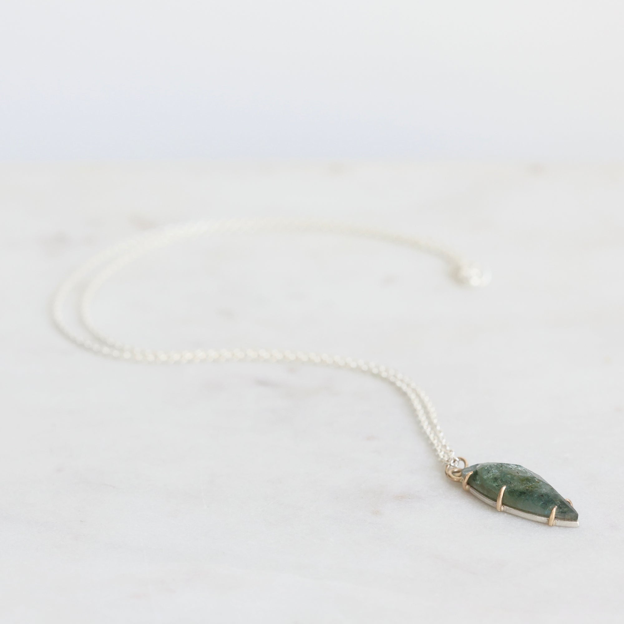 Necklace with a green stone pendant on a light gray background