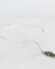 Necklace with a green stone pendant on a light gray background