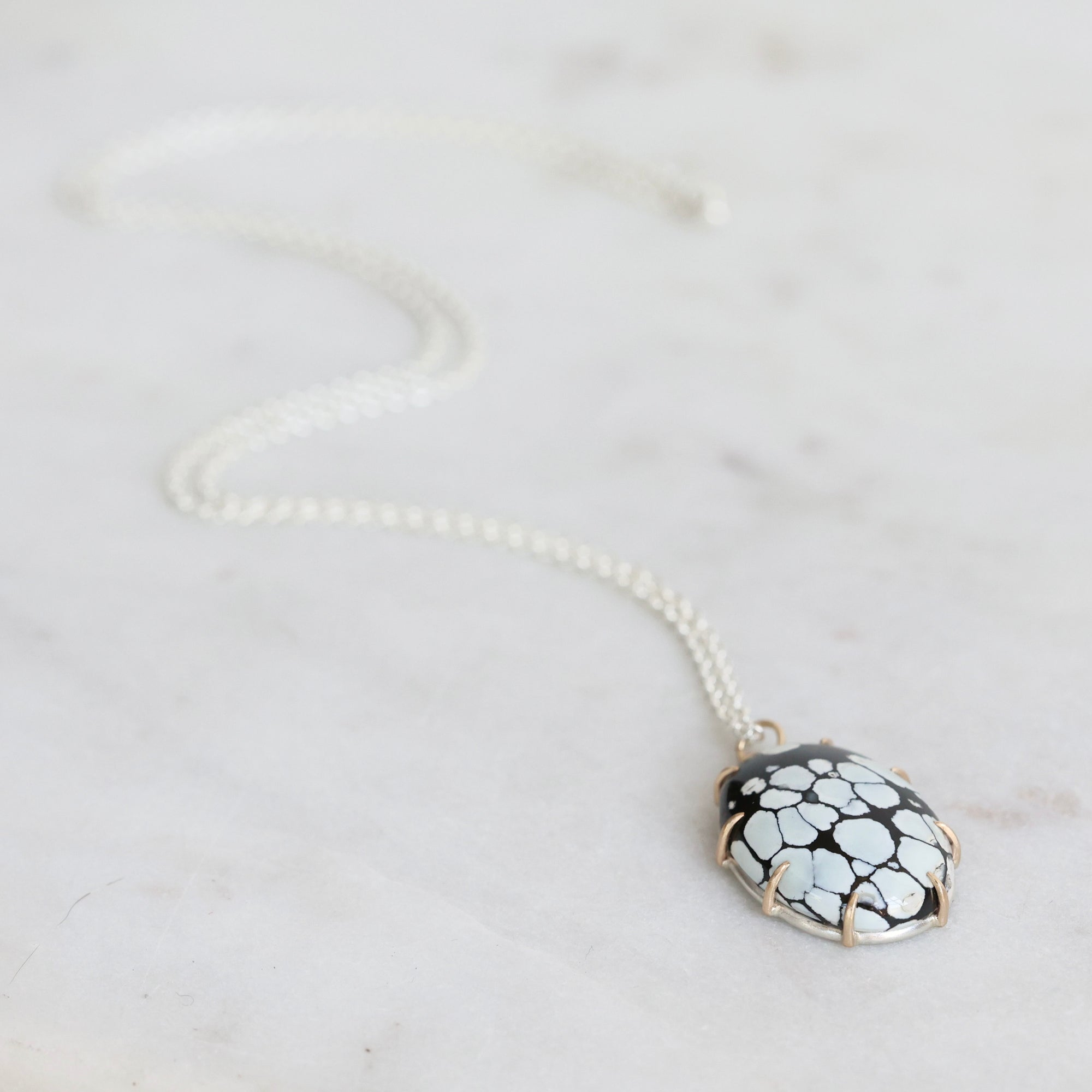 Necklace with a black and white patterned pendant on a light gray background