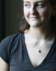 Woman wearing a necklace with a pendant against a dark background